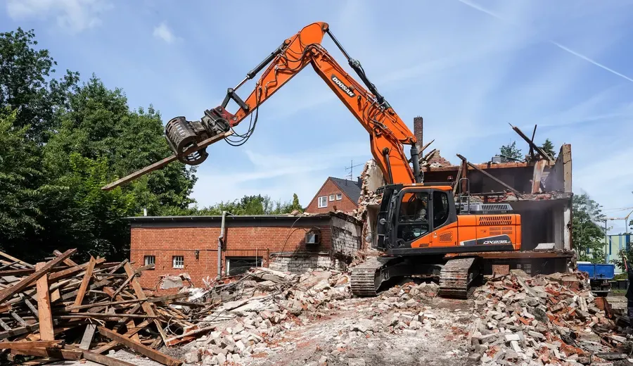 Excavator taking down a brick outbuilding